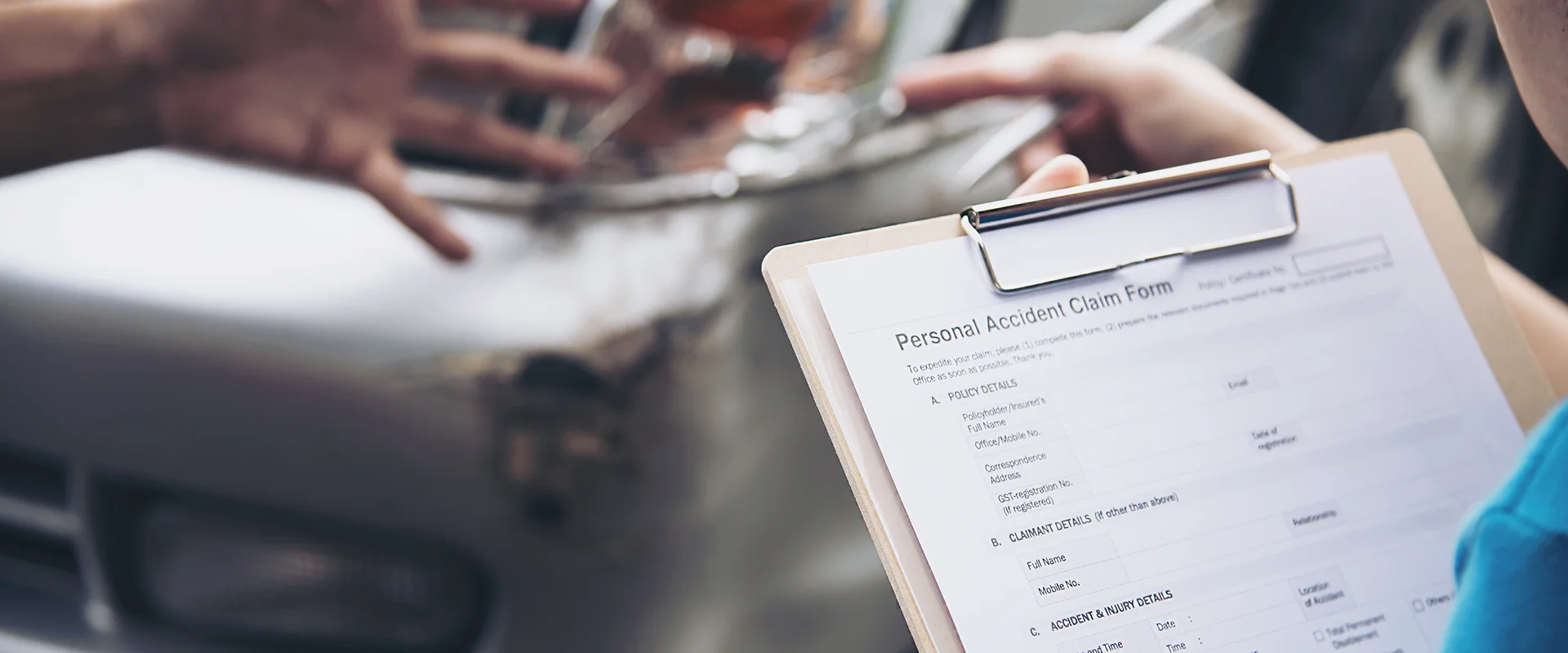 An insurance agent holding a claim form next to a damaged silver car with a broken headlight.