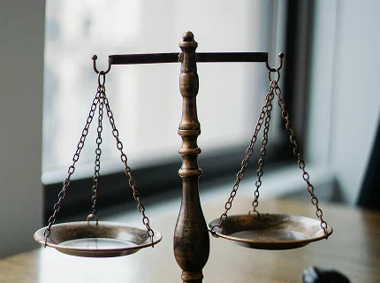 A close-up of a vintage bronze-colored scale of justice sitting on a wooden table.